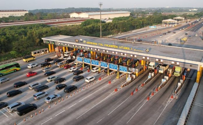 Ilustrasi gerbang tol Trans Jawa yang padat kendaraan saat periode mudik Lebaran dengan pengumuman diskon tarif tol 30 persen.