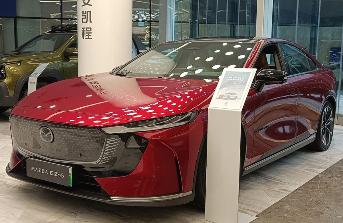 Mobil sedan listrik Mazda EZ-6 dengan balutan stiker kamuflase sedang melakukan uji jalan di jalanan Indonesia sebelum peluncuran resmi.